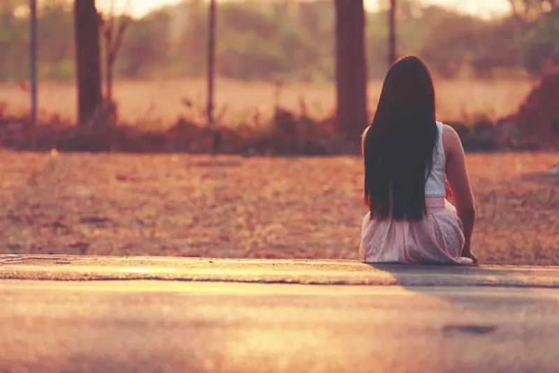 woman with long hair sitting alone outdoor