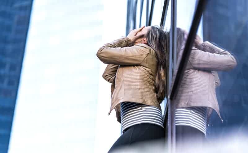 worried woman leaning on glass window