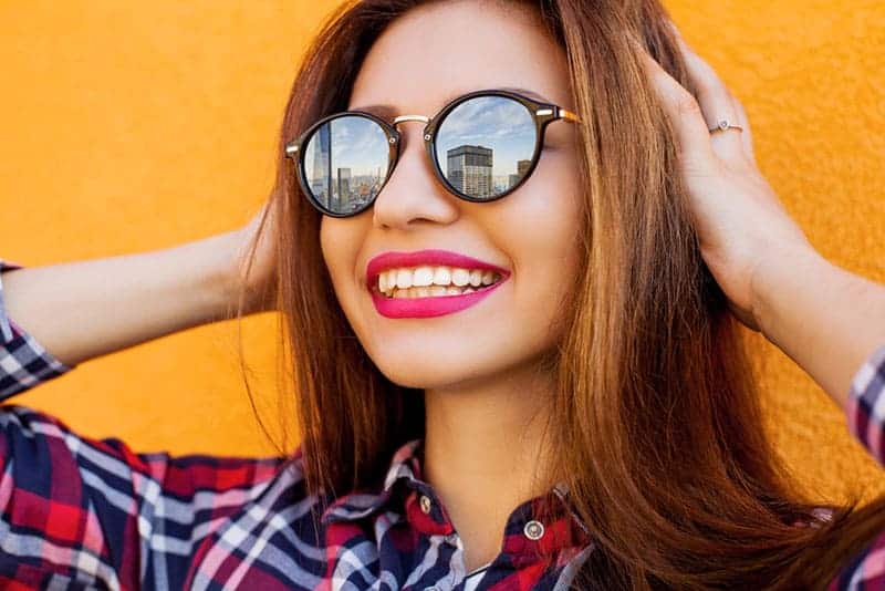 joven morena sonriente con gafas de sol al aire libre