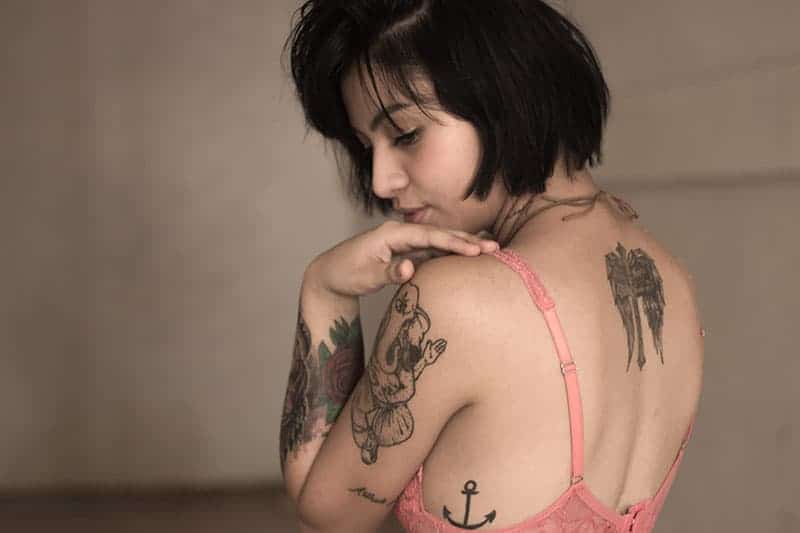 young woman wearing bra having tattoo