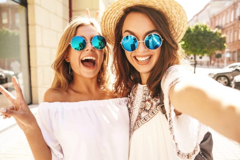 sonriendo dos mujeres con gafas de sol tomando selfie