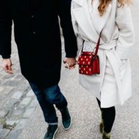 couple holding hands and walking on street