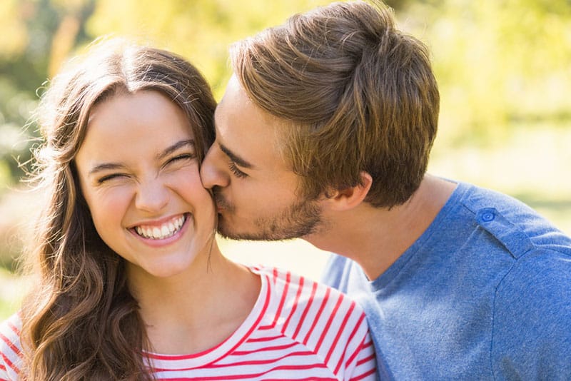 Linda pareja besándose en el parque en un día soleado