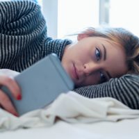 sad woman lying with phone in hands