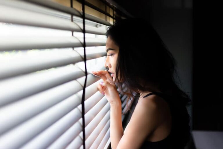 worried woman looking through the window
