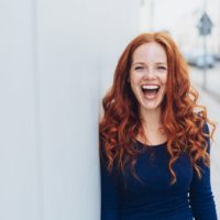 a woman with reddish long hair laughs