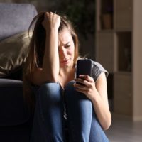 crying woman reading a text message