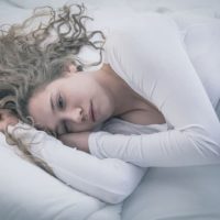 depressed woman lying in bed