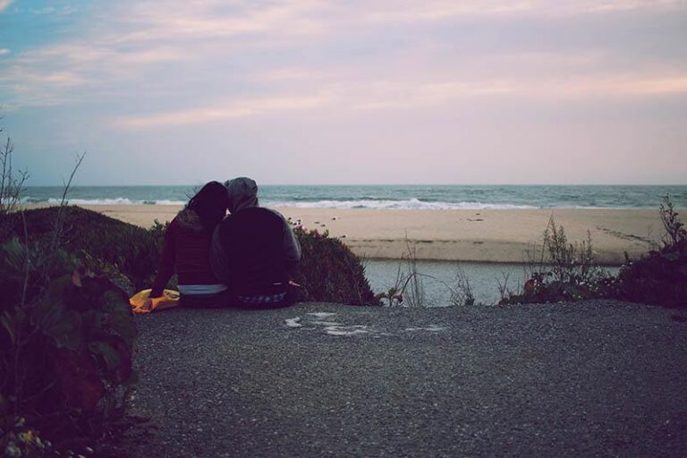 back view of couple sitting in front of water