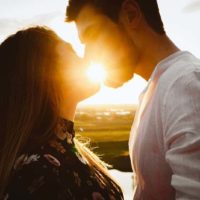pareja besándose durante la puesta de sol