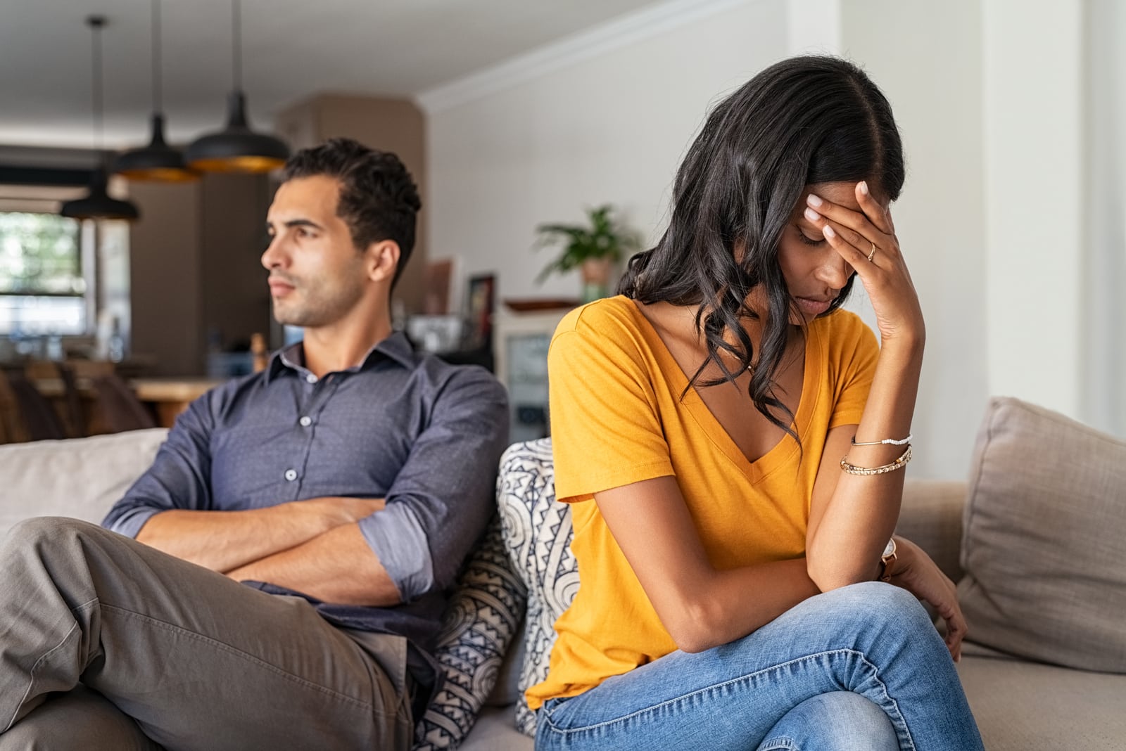 Middle eastern young couple sitting on couch after a fight