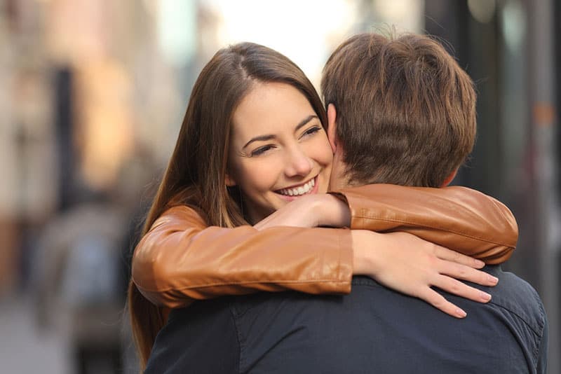 Retrato de um casal feliz abraçado na rua, com o rosto da mulher em primeiro plano