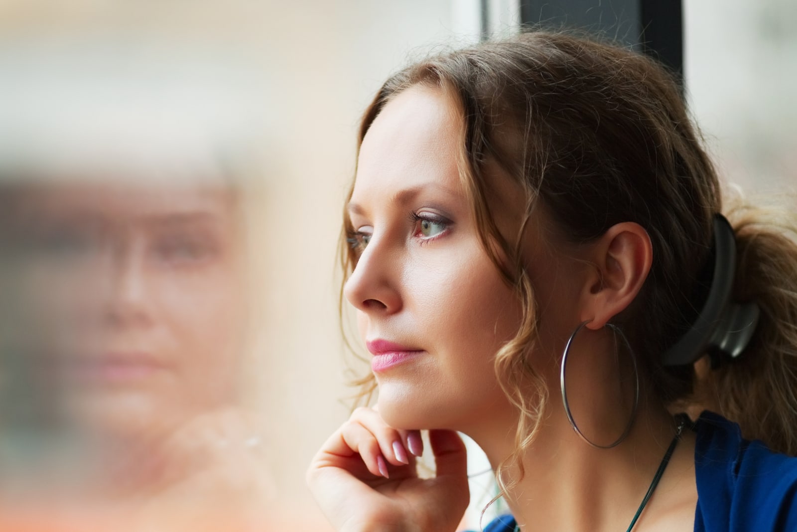 Triste hermosa mujer mirando a través de una ventana