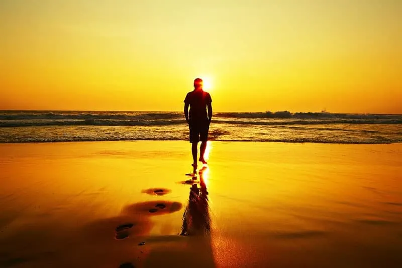 Silhouette of young man on the beach at sunset.