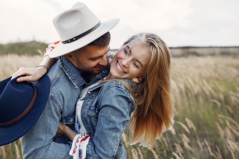 a happy loving couple hugging in a field of wheat