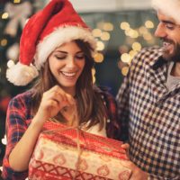 una pareja feliz abre un regalo de Navidad