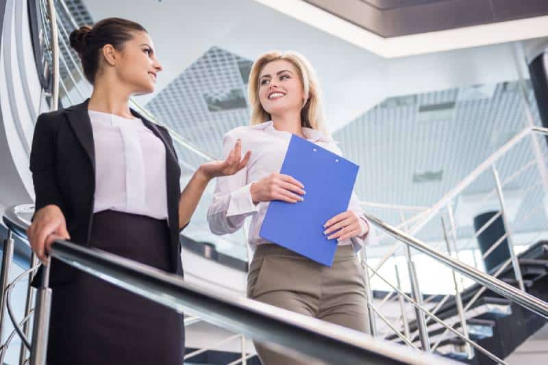 Two attractive business woman walking down the stairs and talking.