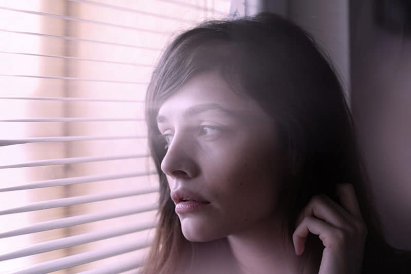 Ritratto di donna; ritratto ravvicinato di una giovane donna che guarda attraverso la finestra.