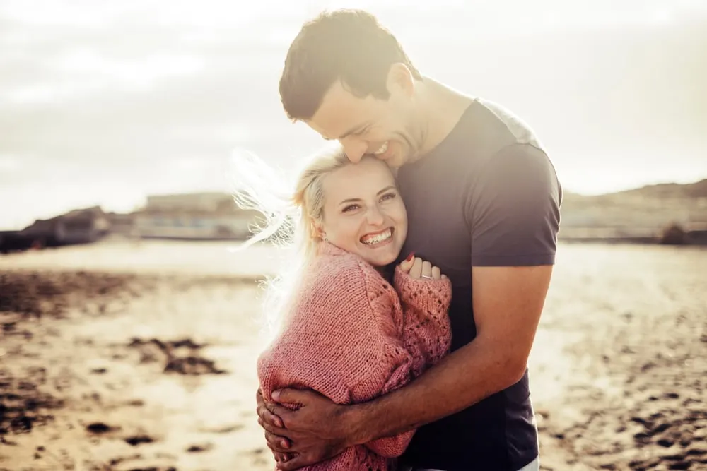 a beautiful young couple hugging on the beach