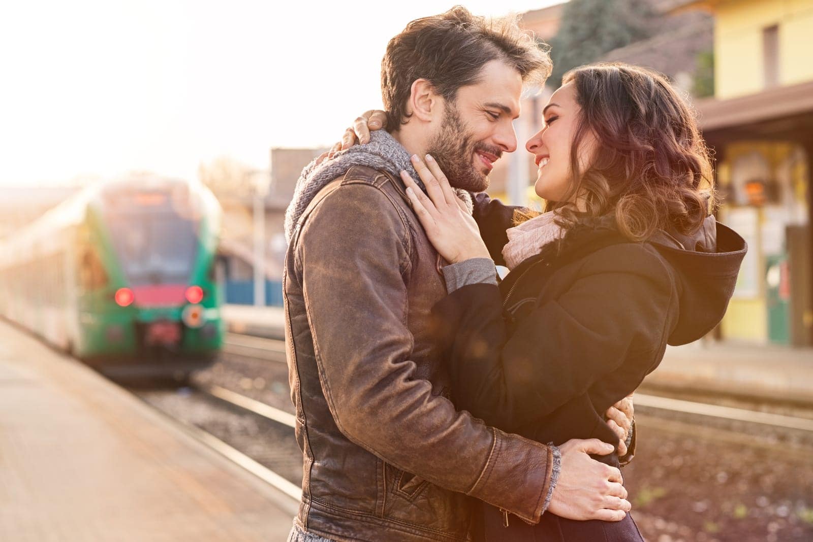 una pareja de enamorados en una estación de tren abrazándose y besándose