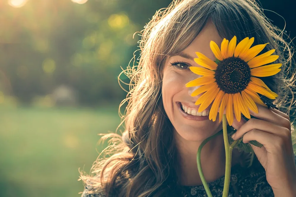a portrait of a smiling girl holding a sunflower flower