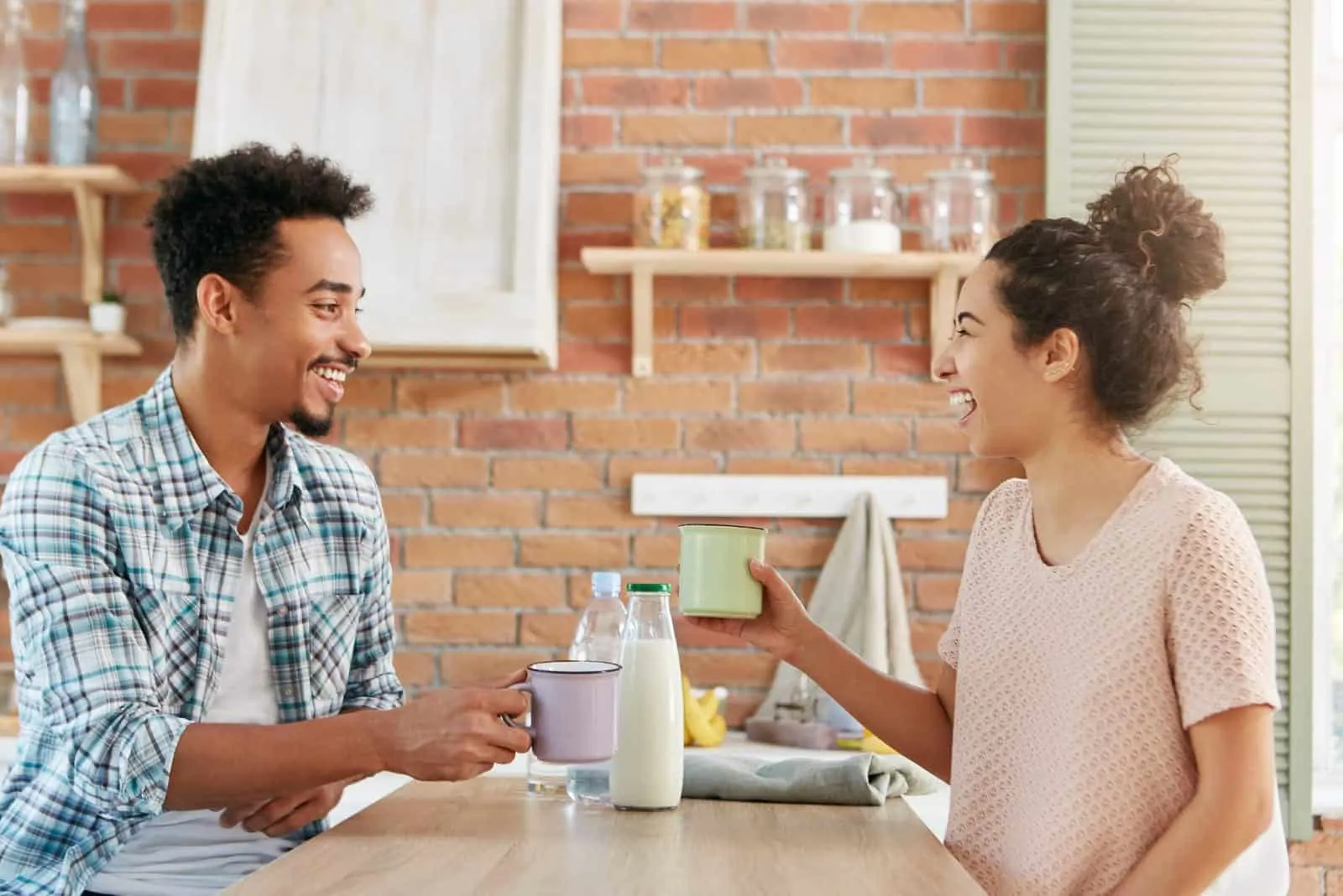 a smiling couple talking in the kitchen over breakfast