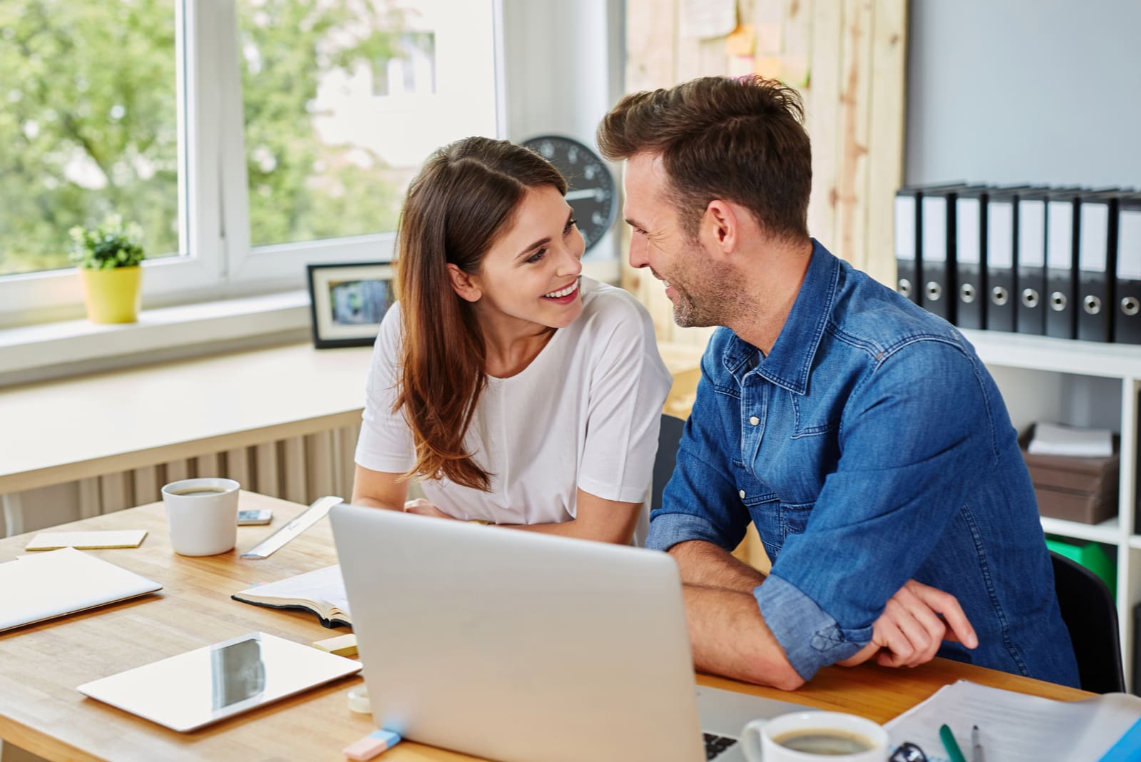 a smiling loving couple doing something on a laptop