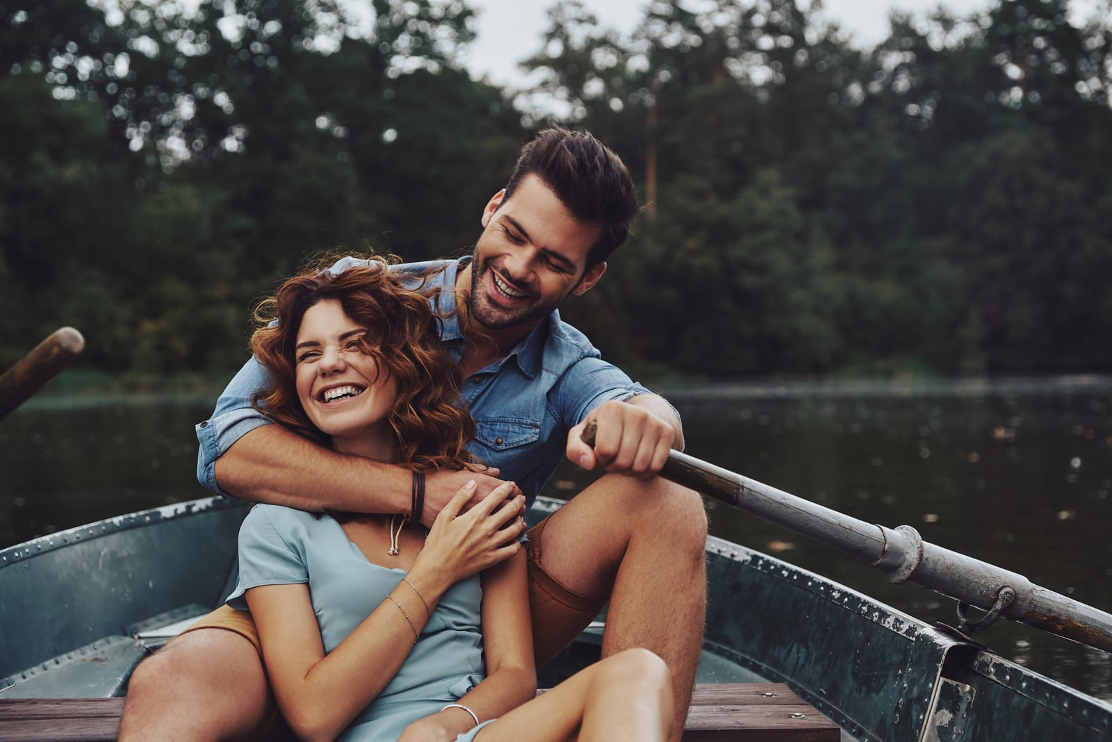 um casal sorridente e amoroso abraça-se e anda de caiaque