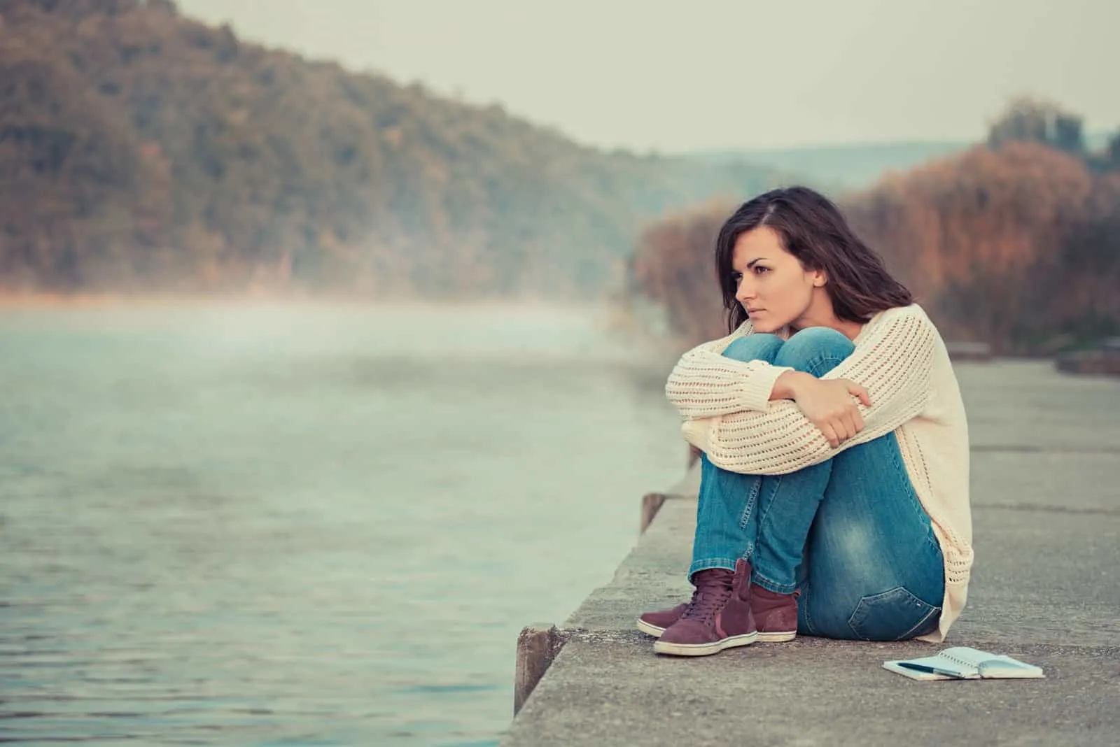 a woman sitting on a lake dock