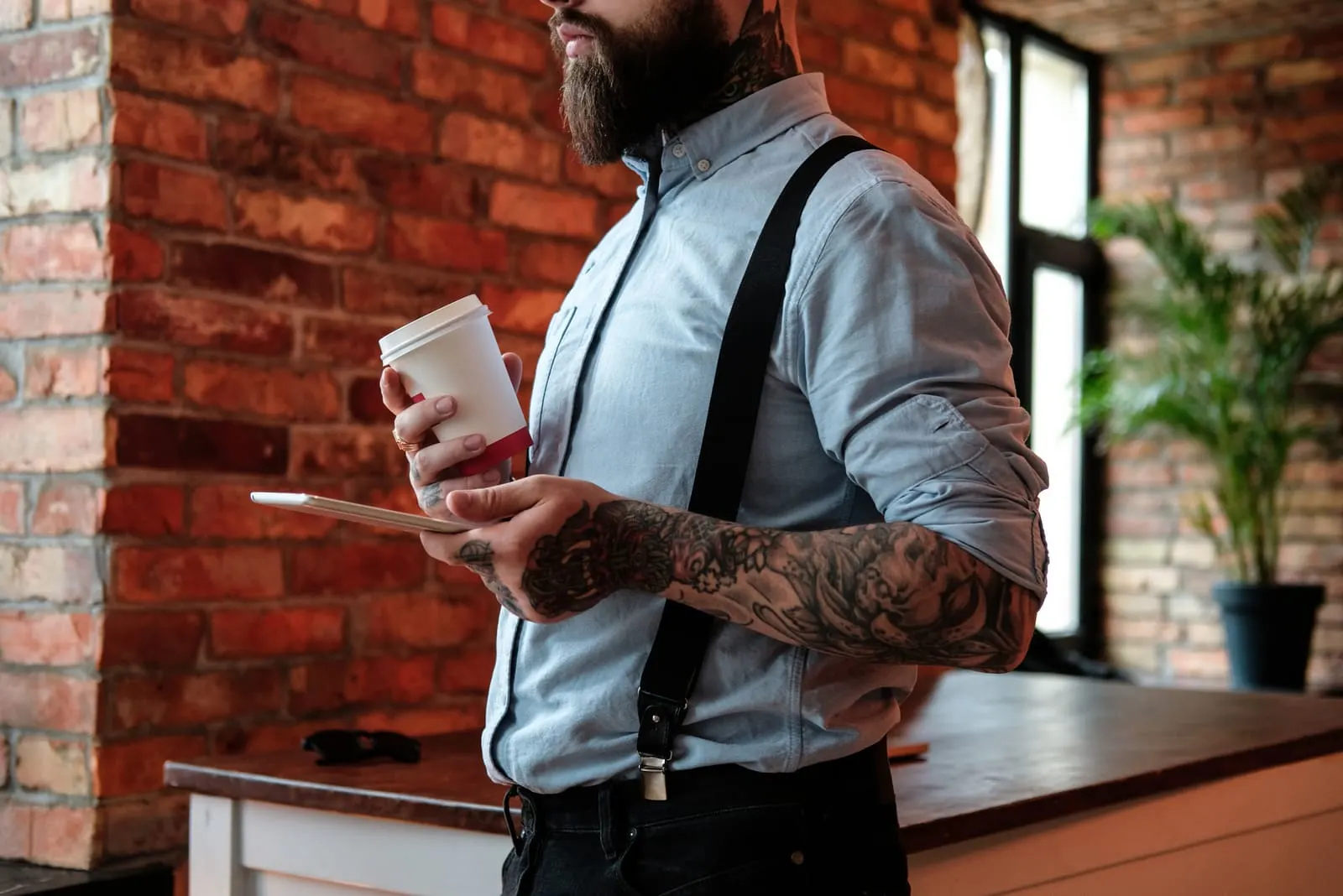 bearded man holding coffee and his phone