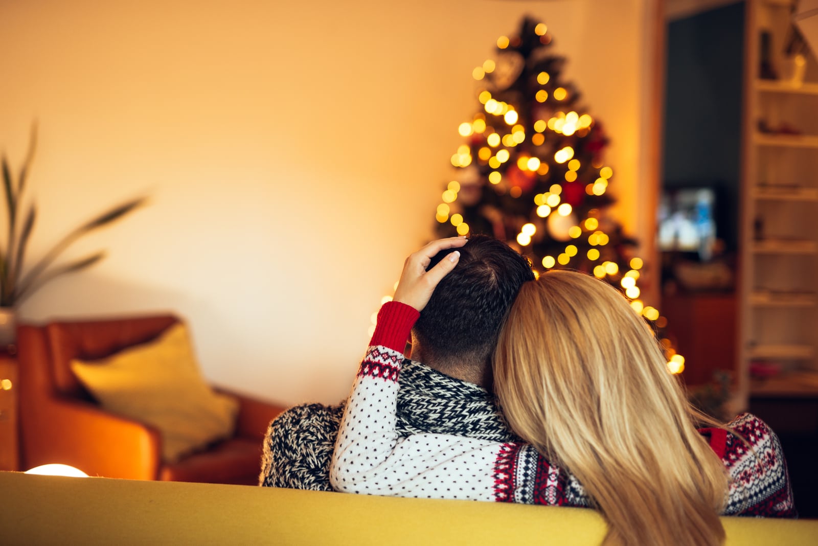 couple cuddling while sitting on a sofa