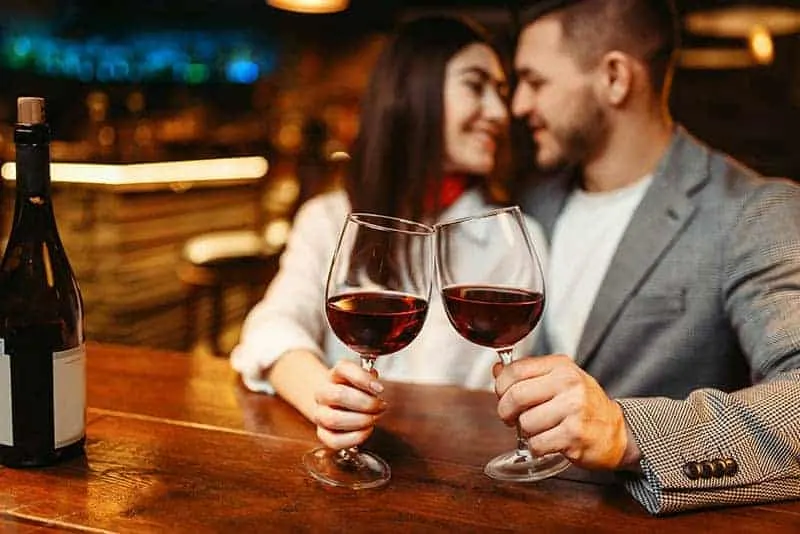 couple holding glass of wine in the bar