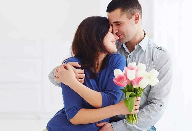 couple hugging at home woman holding a flowers