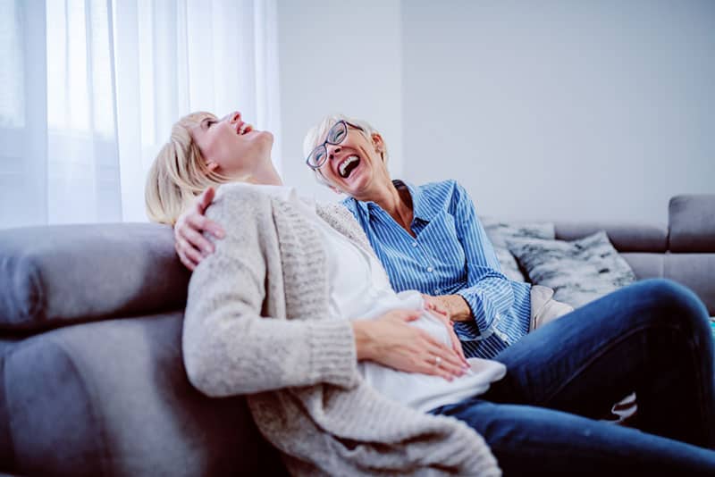 daughter and mother laughing on the couch