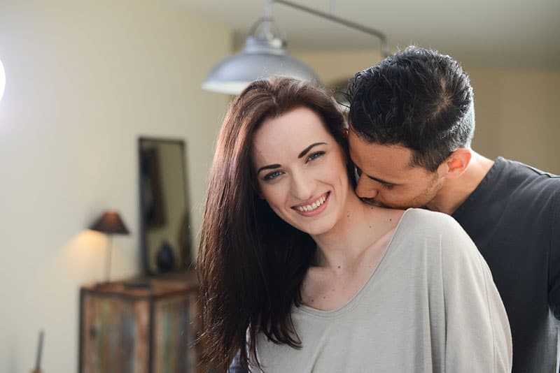 handsome young man kissing beautiful young girlfriend in her neck