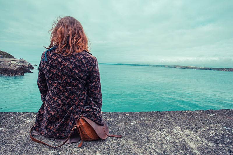 donna sola seduta in riva al mare