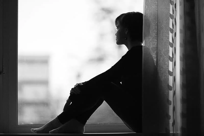 lonely woman sitting on the window