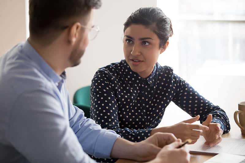 male and female talking at desk