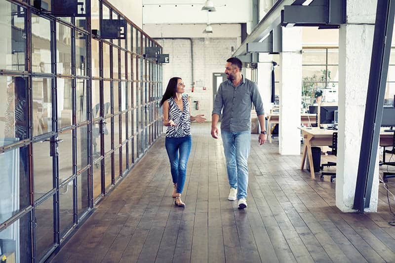 uomo e donna che si guardano e camminano in ufficio