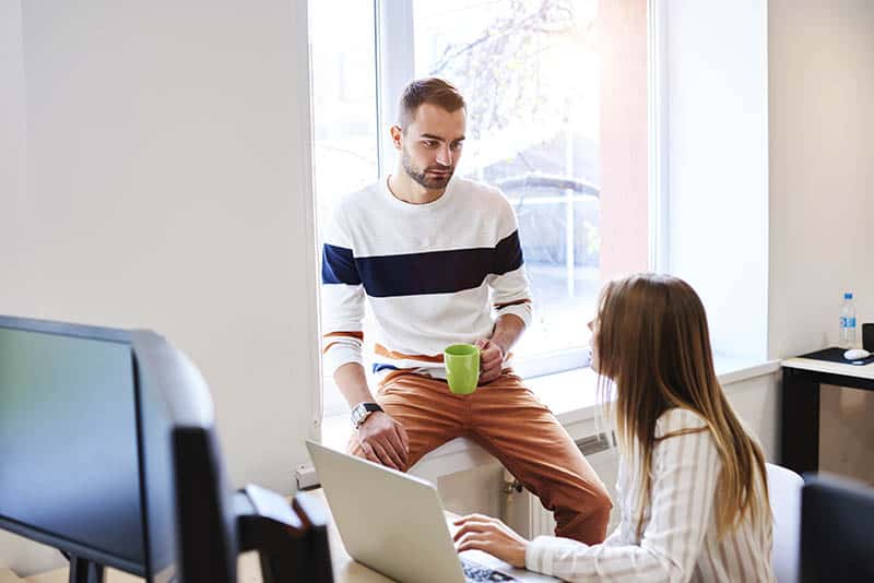 man holds cup of tea and talking to woman