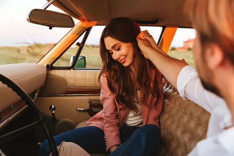 man touching woman's hair in car