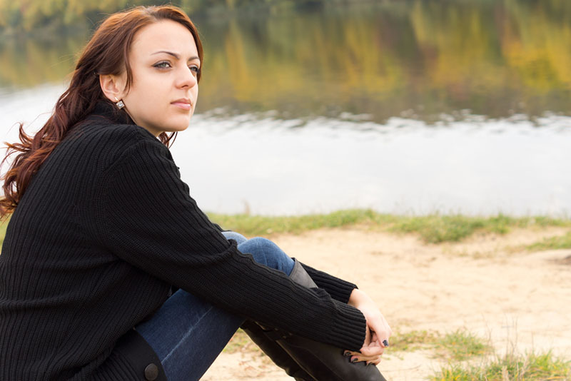 donna seria seduta vicino al fiume