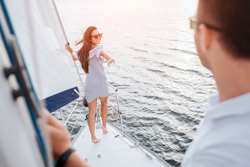 Una modella bella e ben fatta è in piedi a prua di uno yacht e si tiene al tubo. Guarda dietro di sé il fidanzato. La bruna cerca di raggiungerlo con la mano e sorride. Il giovane si alza e guarda.