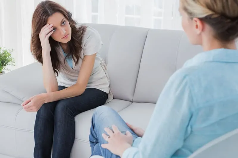 Upset woman sitting on the couch and looking at therapist in a private session