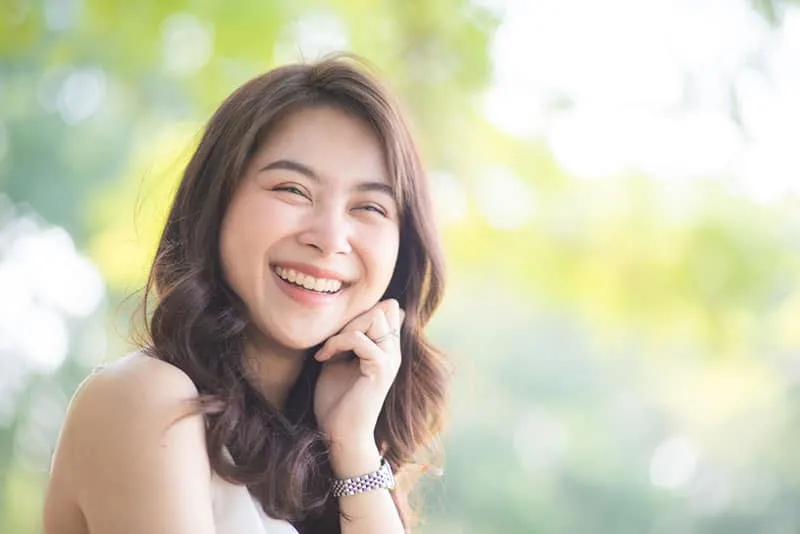 Portrait of smiling beautiful asian women in park morning light with bokeh half body portrait