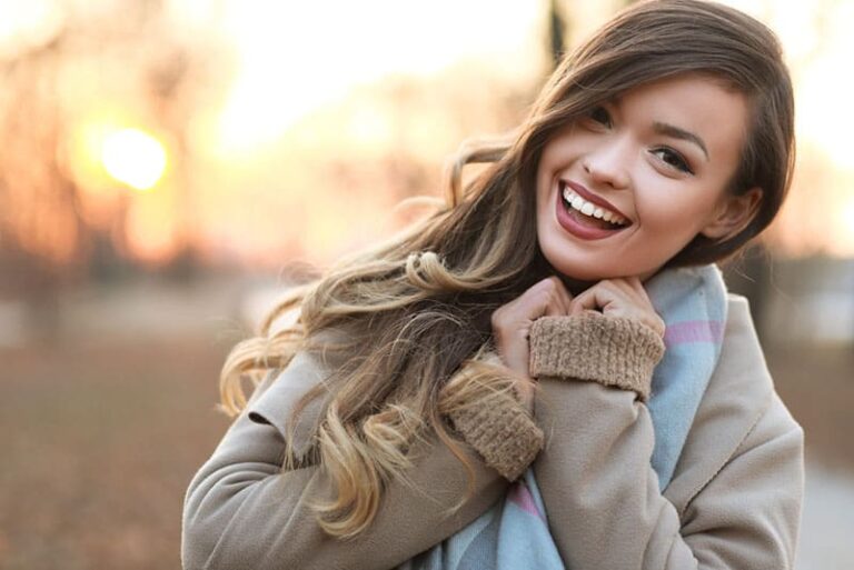half length portrait of young happy woman walking in the street on sunset