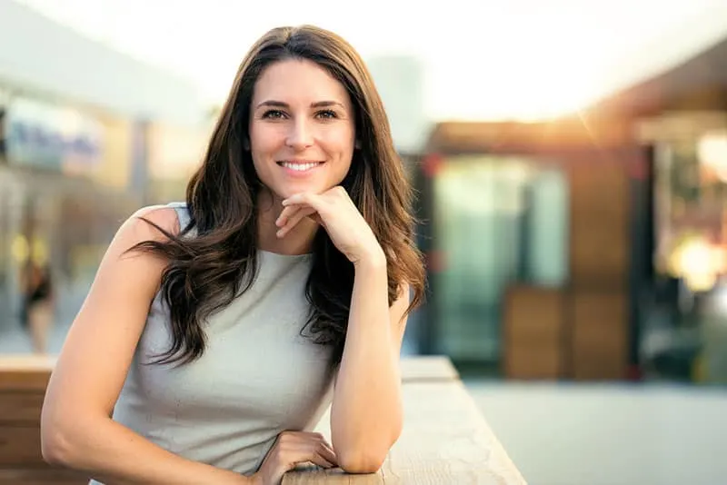 Genuine natural portrait of brunette woman happy and smiling on rooftop of new modern home
