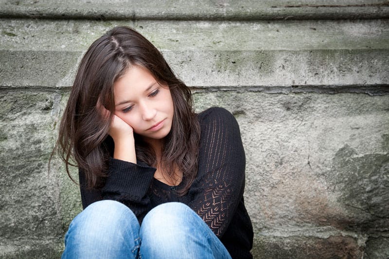 Ritratto all'aperto di un'adolescente triste che guarda pensierosa ai suoi problemi