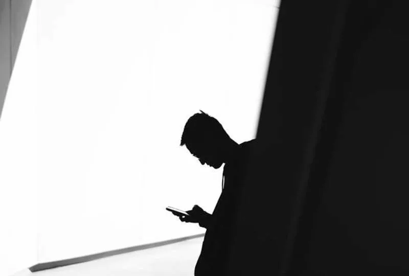 silhouette of man looking on his phone