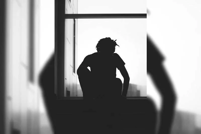 silhouette of man sitting beside window